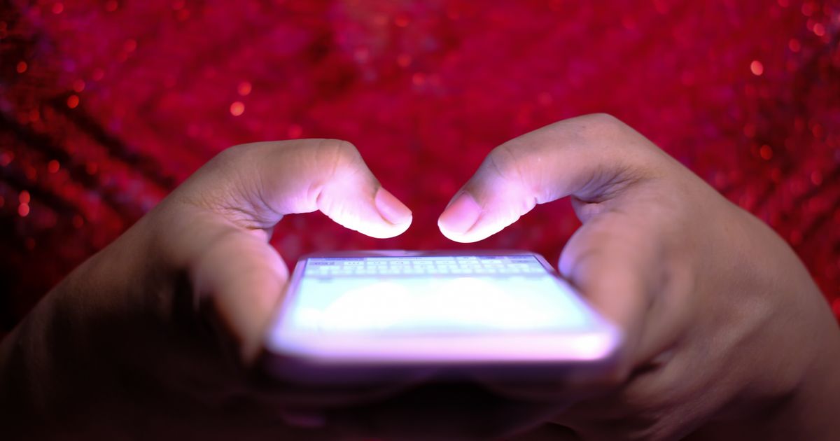Hands typing a reply on a smartphone with a glowing screen