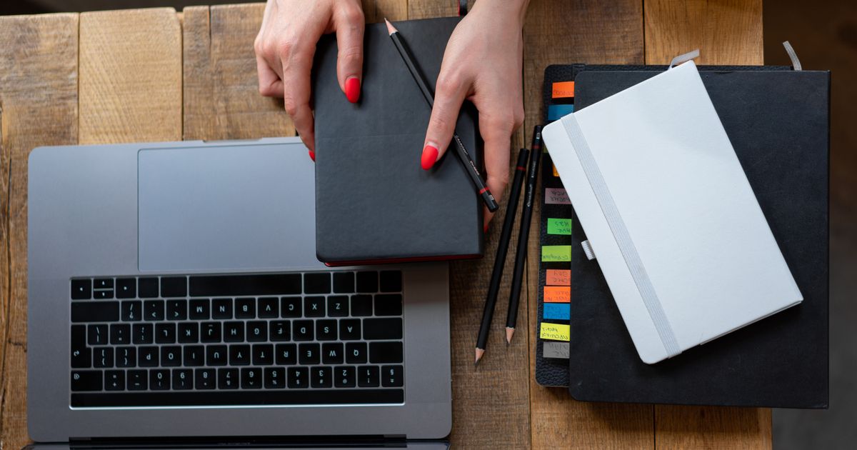 Overhead view of a desk with laptop, planner and notebooks